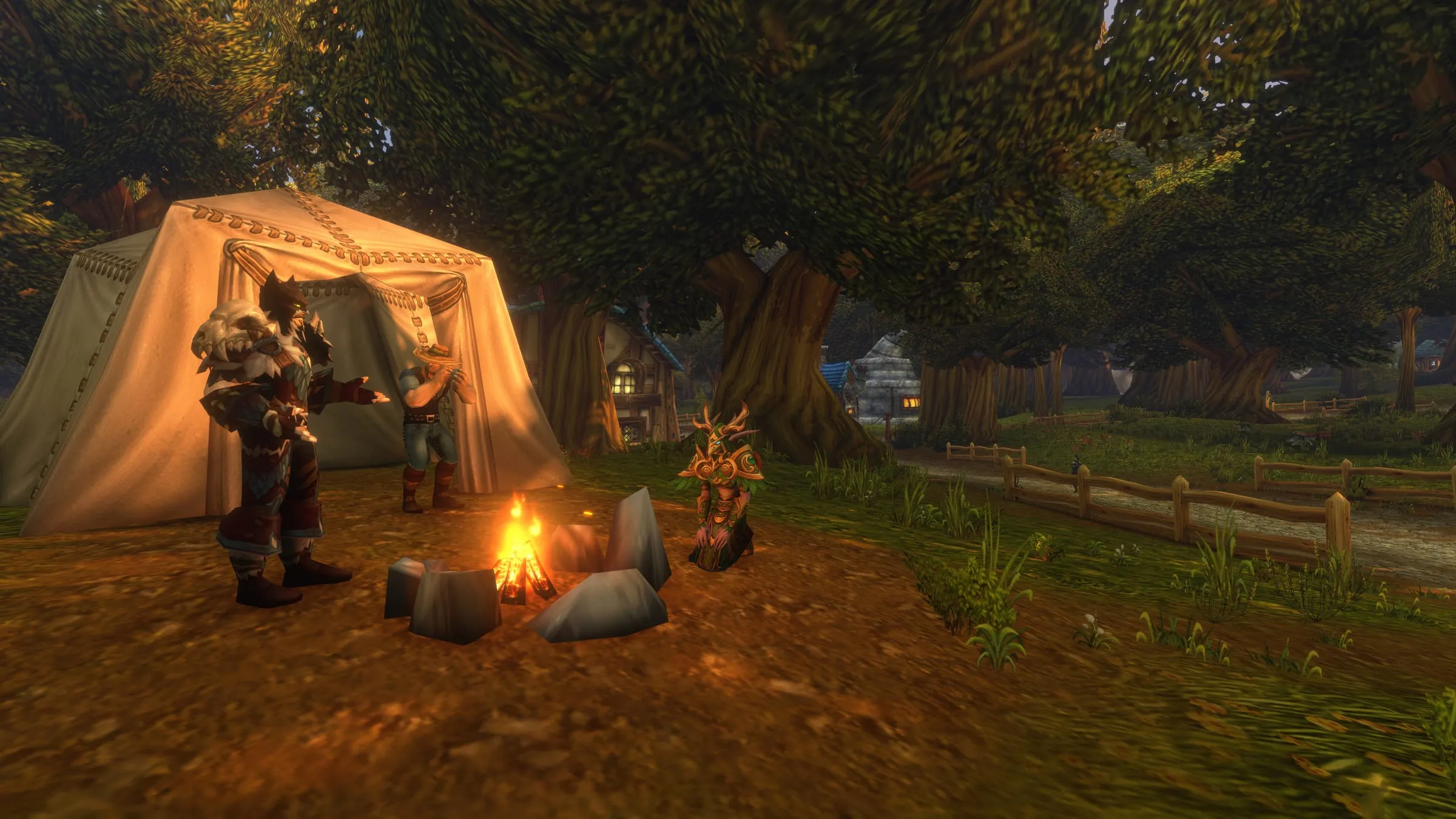 Players gathered at a campfire and tent beneath a broad tree at dusk